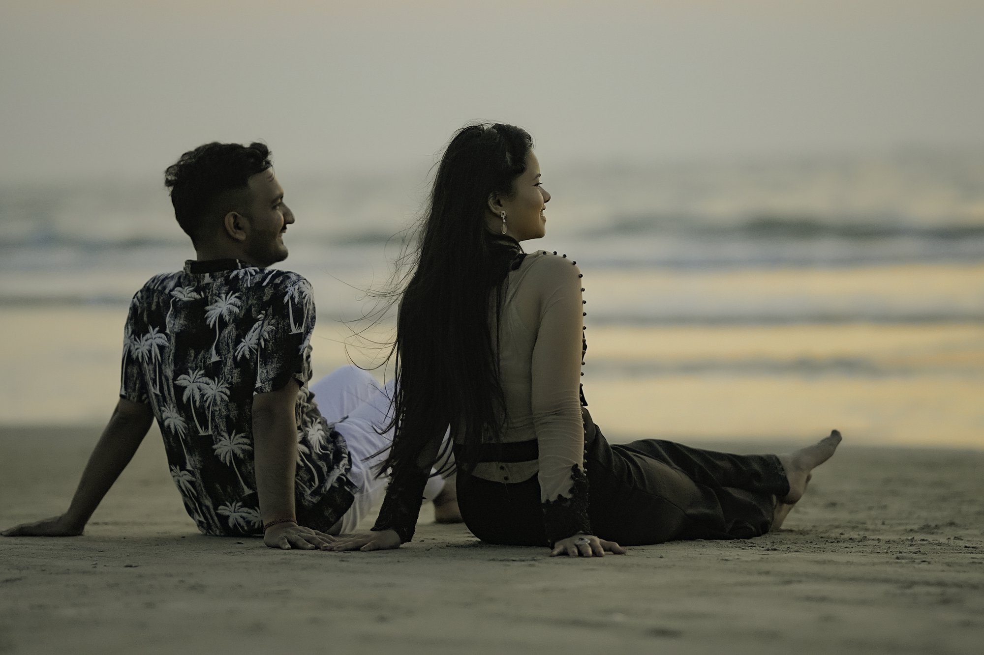 Embracing the moment—engaged couple strolling along the waves, admiring the evening sky.